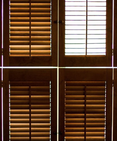 Close up view of dark wood plantation shutters with one of them opened up.